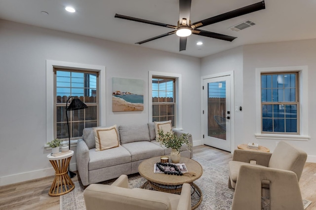 living room with recessed lighting, visible vents, light wood finished floors, and baseboards