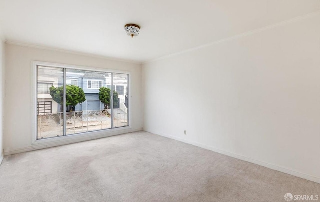 carpeted empty room featuring baseboards and crown molding