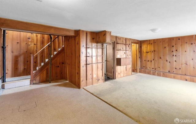 empty room featuring tile patterned floors, stairway, and wooden walls