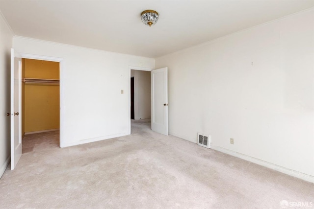 unfurnished bedroom with visible vents, ornamental molding, a closet, light colored carpet, and a spacious closet