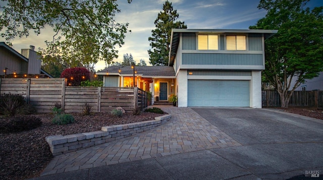 view of front of house featuring a garage, driveway, and fence