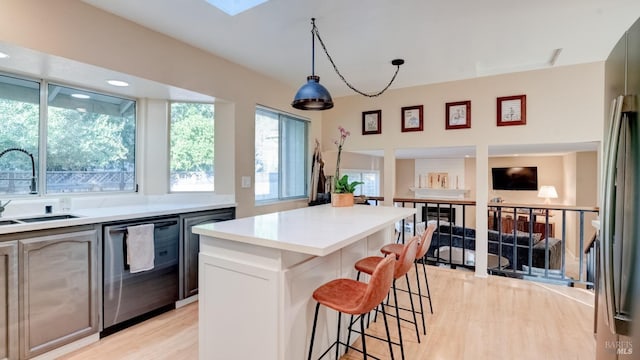 kitchen with a kitchen bar, a sink, a kitchen island, light countertops, and dishwasher