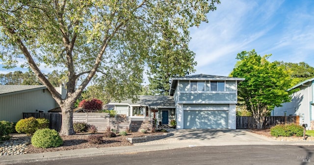 view of front facade featuring a fenced front yard, concrete driveway, and a garage