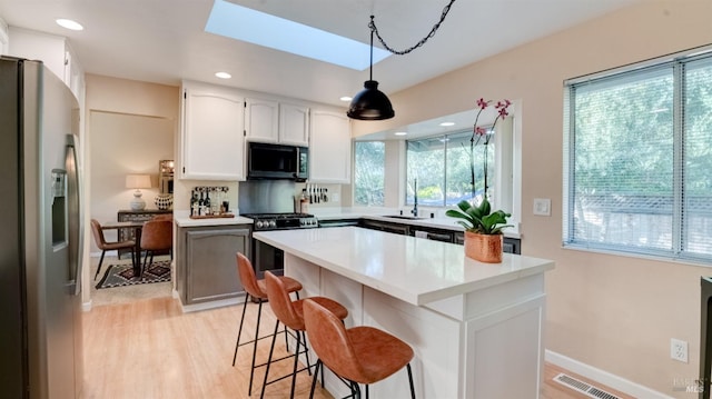 kitchen featuring visible vents, black microwave, stainless steel fridge with ice dispenser, gas stove, and a sink