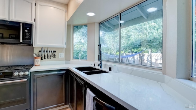 kitchen with black microwave, stainless steel gas range, recessed lighting, white cabinetry, and a sink