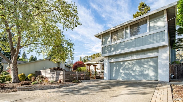 view of front of property with a garage, concrete driveway, and fence