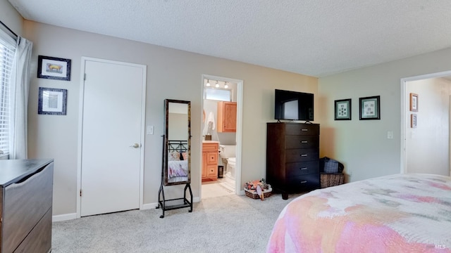 carpeted bedroom with baseboards, ensuite bathroom, and a textured ceiling