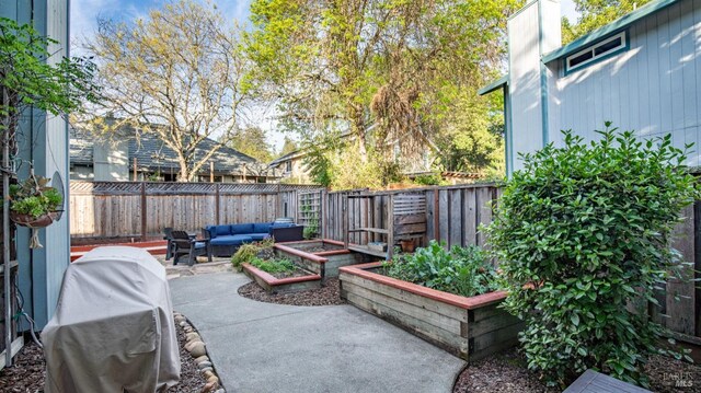 view of patio with a fenced backyard, a grill, outdoor lounge area, and a vegetable garden