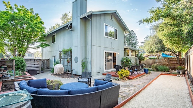 back of house featuring an outdoor living space, a patio area, a fenced backyard, and a chimney