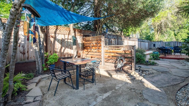 view of patio / terrace with outdoor dining space, a fenced backyard, and a wooden deck