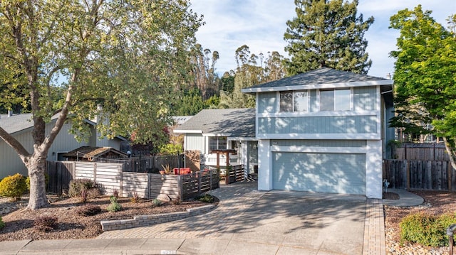 view of front of home with fence, a garage, driveway, and roof with shingles