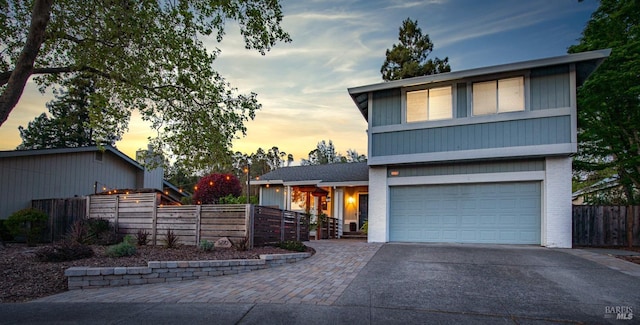 view of front facade featuring brick siding, driveway, a garage, and fence