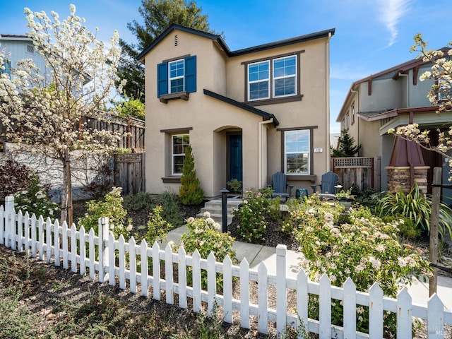 traditional-style house featuring a fenced front yard and stucco siding