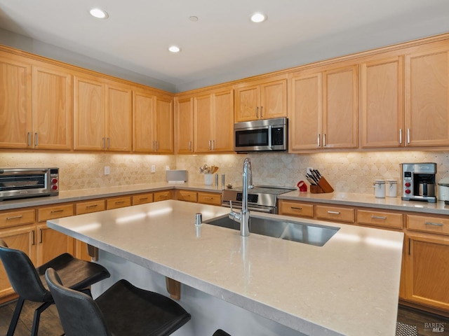 kitchen with a toaster, stainless steel microwave, backsplash, and a kitchen bar