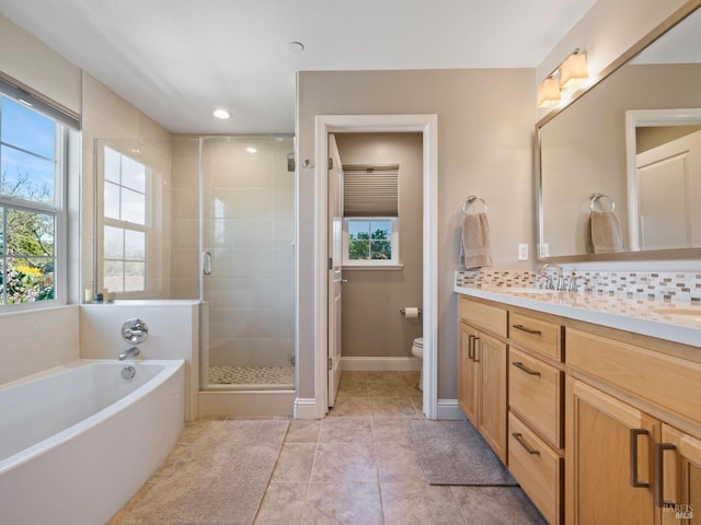 bathroom featuring toilet, a stall shower, tasteful backsplash, double vanity, and a bath