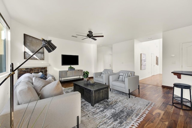 living area featuring visible vents, baseboards, dark wood-type flooring, and ceiling fan