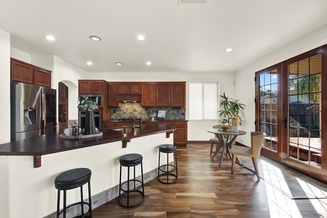 kitchen featuring a sink, arched walkways, dark countertops, and appliances with stainless steel finishes