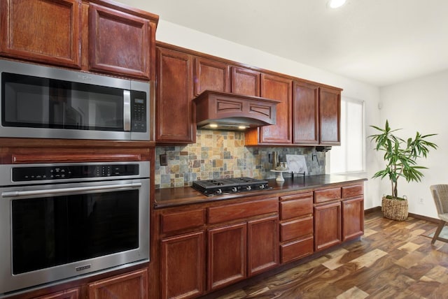 kitchen with dark countertops, baseboards, dark wood finished floors, decorative backsplash, and stainless steel appliances