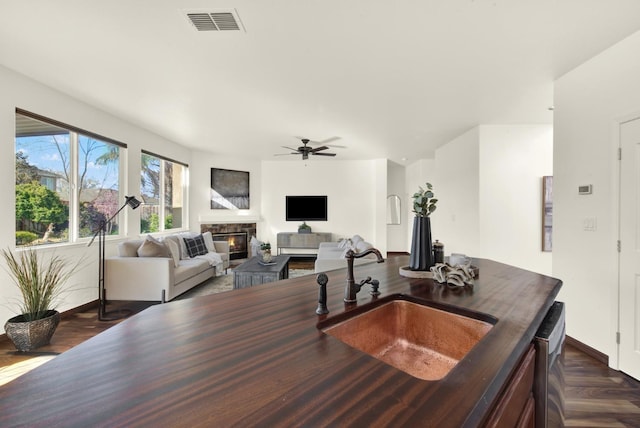 interior space with visible vents, baseboards, a glass covered fireplace, and a ceiling fan