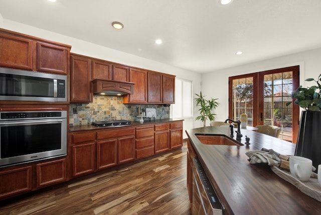 kitchen with a sink, stainless steel appliances, a wealth of natural light, and decorative backsplash