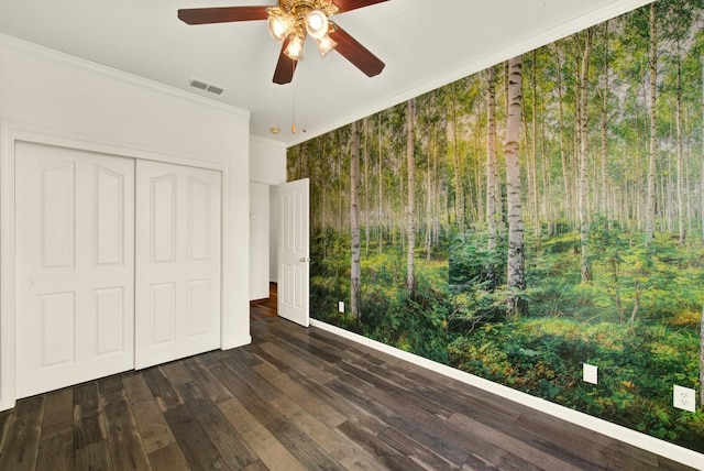 unfurnished bedroom featuring visible vents, crown molding, ceiling fan, a closet, and dark wood-style flooring