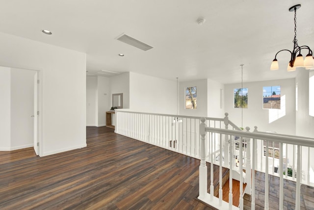 corridor featuring dark wood finished floors, an inviting chandelier, recessed lighting, and baseboards