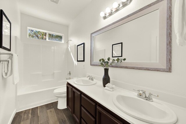 bathroom with a sink, toilet, wood finished floors, and double vanity