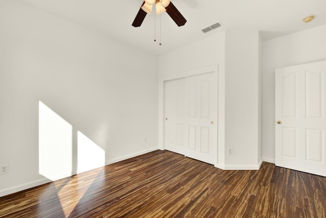 unfurnished room with visible vents, baseboards, and dark wood-style flooring