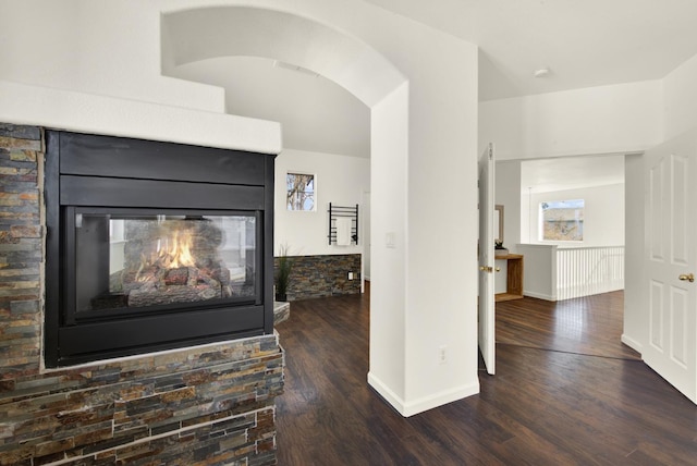 details with arched walkways, a multi sided fireplace, baseboards, and wood finished floors