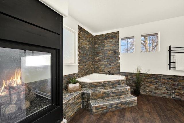 full bathroom featuring a garden tub and wood finished floors