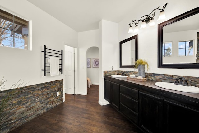 full bathroom with double vanity, wood finished floors, baseboards, and a sink