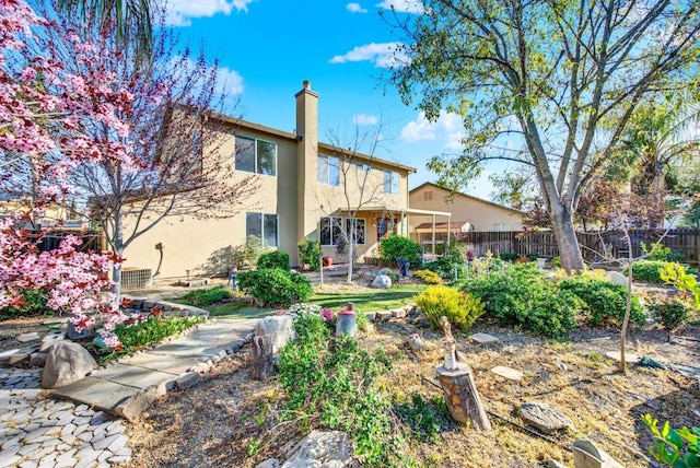 rear view of property featuring fence, a chimney, and stucco siding