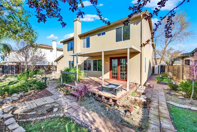 back of house with stucco siding, a fenced backyard, french doors, a chimney, and a patio area