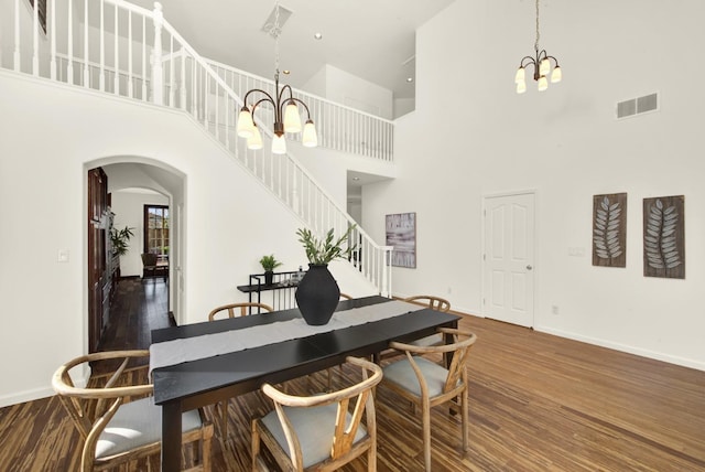 dining area with a chandelier, visible vents, arched walkways, and wood finished floors