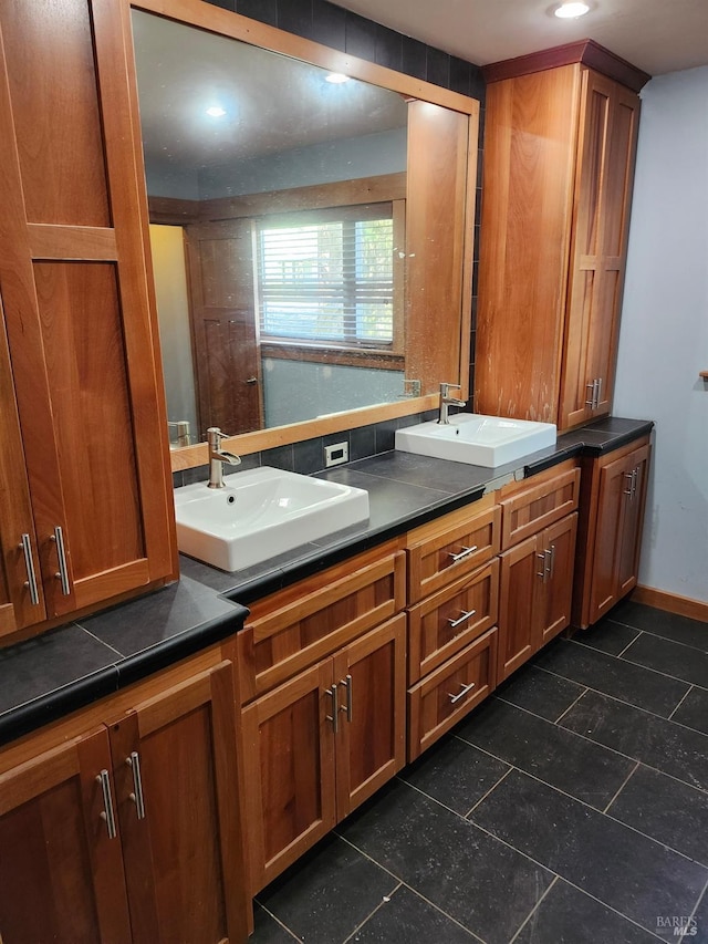 bathroom with tile patterned floors, double vanity, baseboards, and a sink