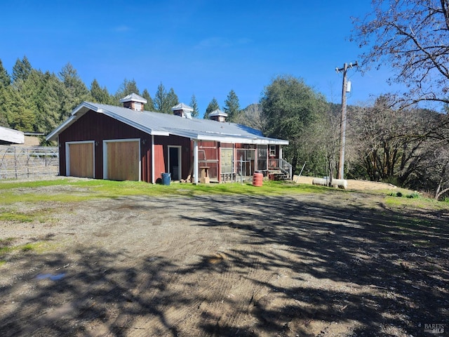 exterior space with an outbuilding, driveway, metal roof, a pole building, and a garage