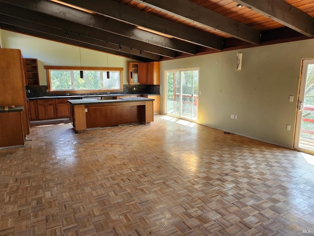 kitchen featuring brown cabinets, backsplash, open floor plan, a center island, and vaulted ceiling with beams