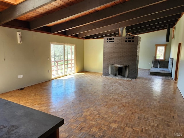 unfurnished living room with beam ceiling, plenty of natural light, a fireplace, and wooden ceiling