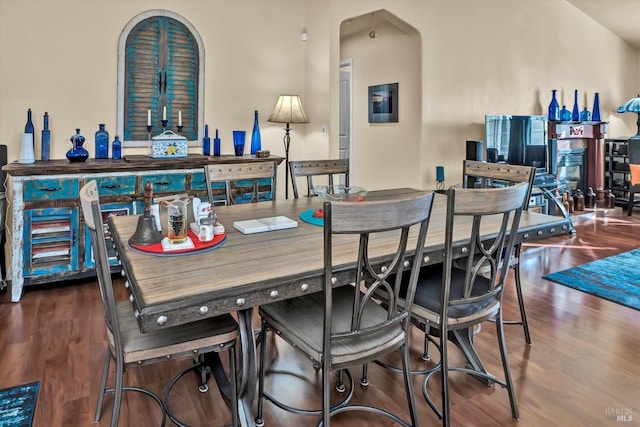 dining space with arched walkways and wood finished floors