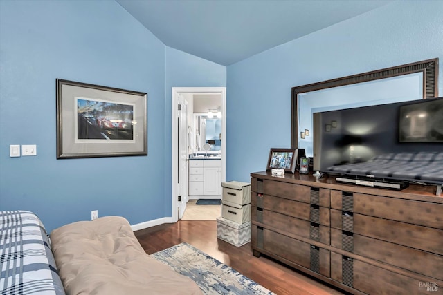 interior space with a sink, baseboards, wood finished floors, and vaulted ceiling