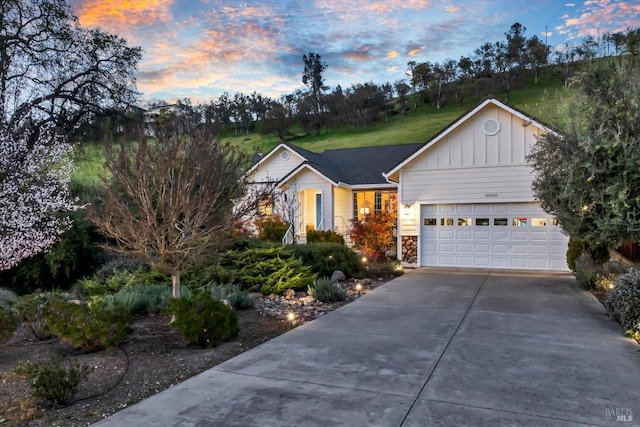 ranch-style house featuring a garage, stone siding, board and batten siding, and concrete driveway