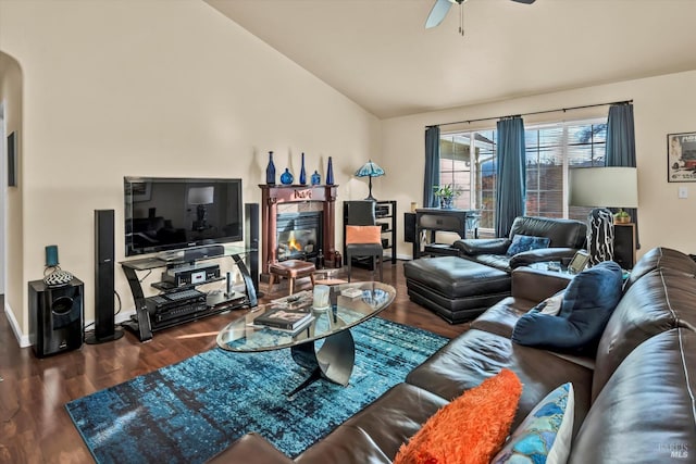 living room featuring a ceiling fan, a glass covered fireplace, wood finished floors, arched walkways, and vaulted ceiling