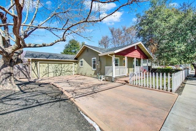 view of front facade with a porch, a fenced front yard, a garage, and driveway