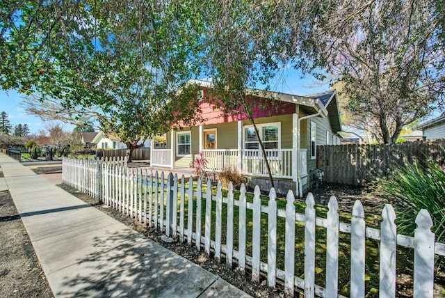 bungalow-style home featuring covered porch and a fenced front yard