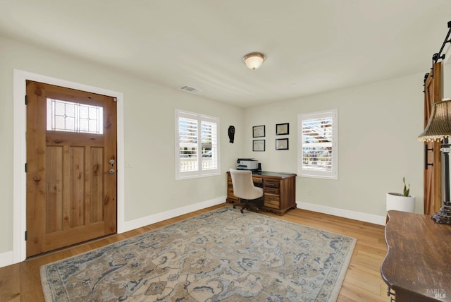 office space with visible vents, baseboards, light wood-style floors, and a healthy amount of sunlight