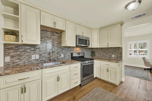 kitchen featuring visible vents, light wood finished floors, a sink, cream cabinetry, and appliances with stainless steel finishes