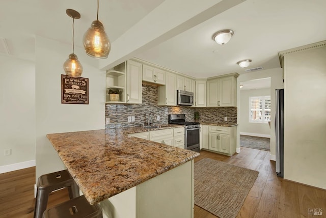 kitchen featuring open shelves, tasteful backsplash, wood finished floors, appliances with stainless steel finishes, and a peninsula