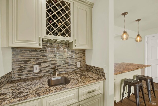 kitchen featuring light stone countertops, backsplash, and cream cabinetry