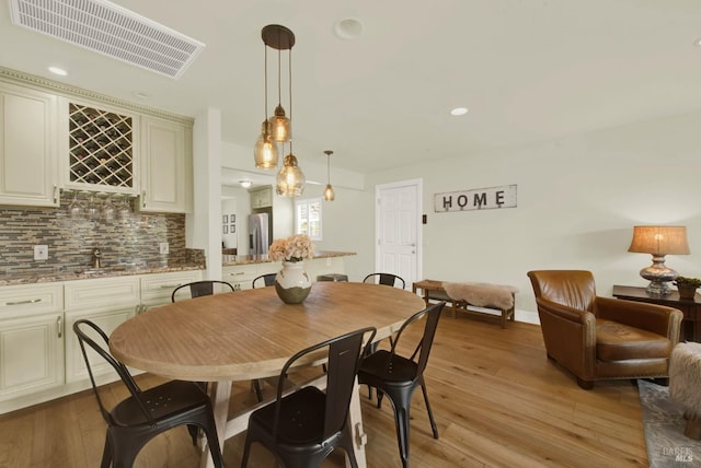 dining area featuring recessed lighting, visible vents, wet bar, and light wood finished floors