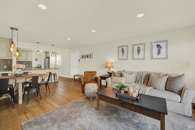 living area with recessed lighting, light wood-type flooring, and baseboards